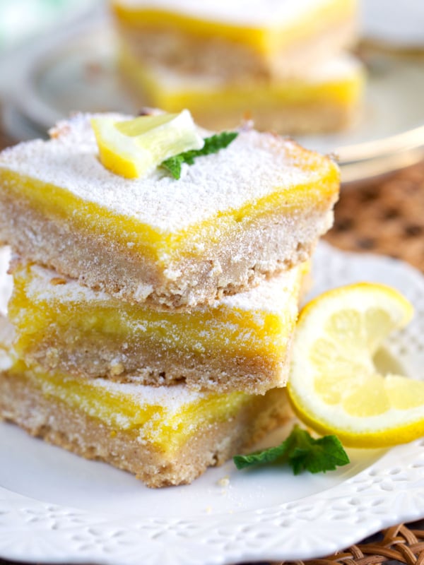 Lemon Bars stacked on a white plate and dusted with powdered sugar.