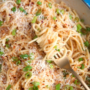 Miso pasta in a cast iron enameled skillet with a gold fork swirled with pasta.