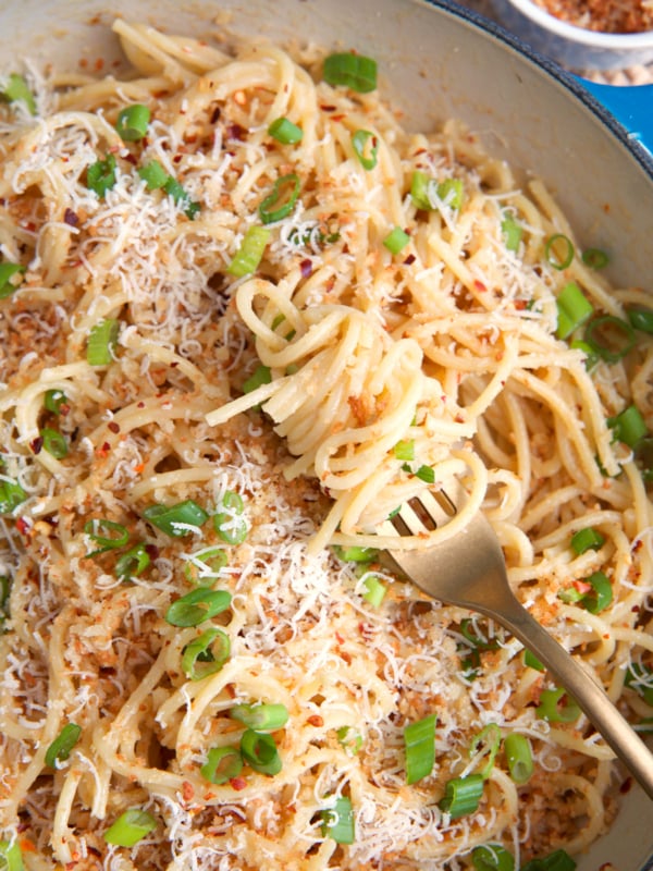 Miso pasta in a cast iron enameled skillet with a gold fork swirled with pasta.