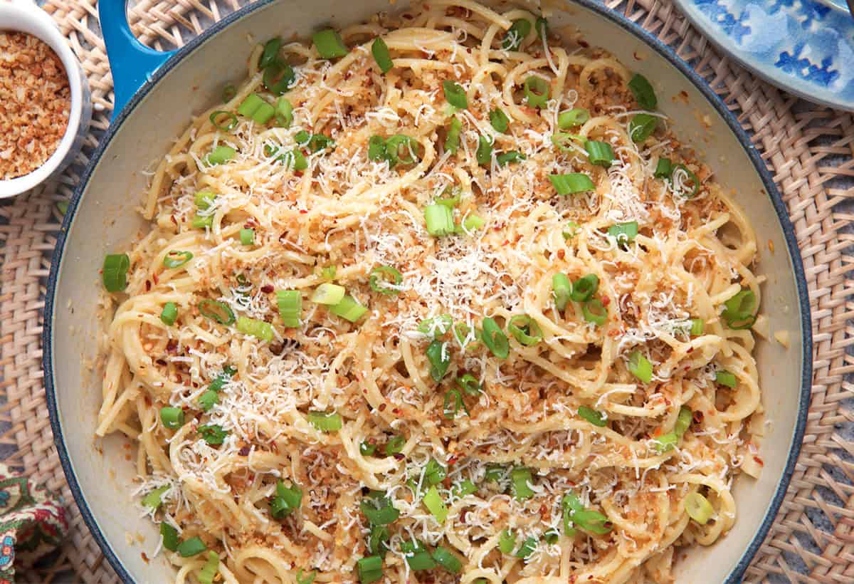 Creamy Miso Pasta topped with cheese, buttery breadcrumbs and scallions in a white skillet.
