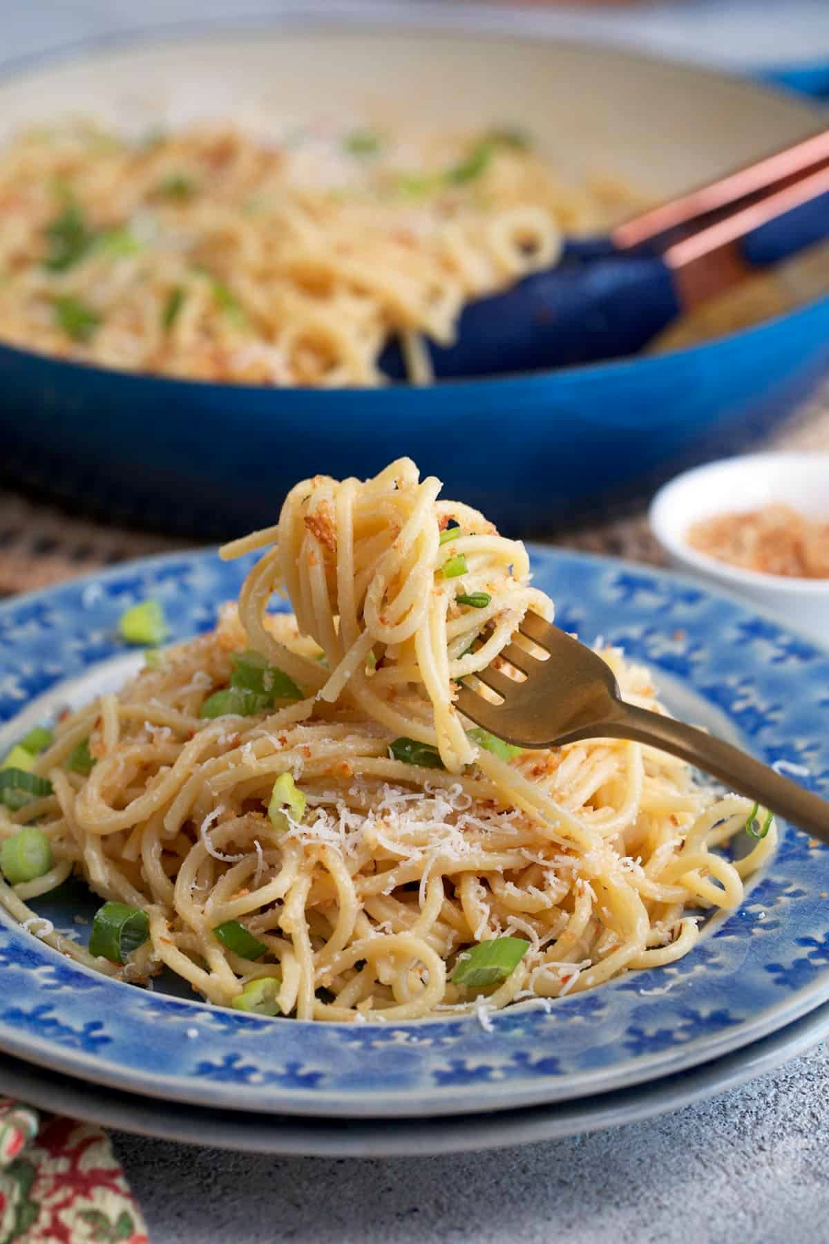 Miso pasta on a blue plate with a gold fork with pasta on it.