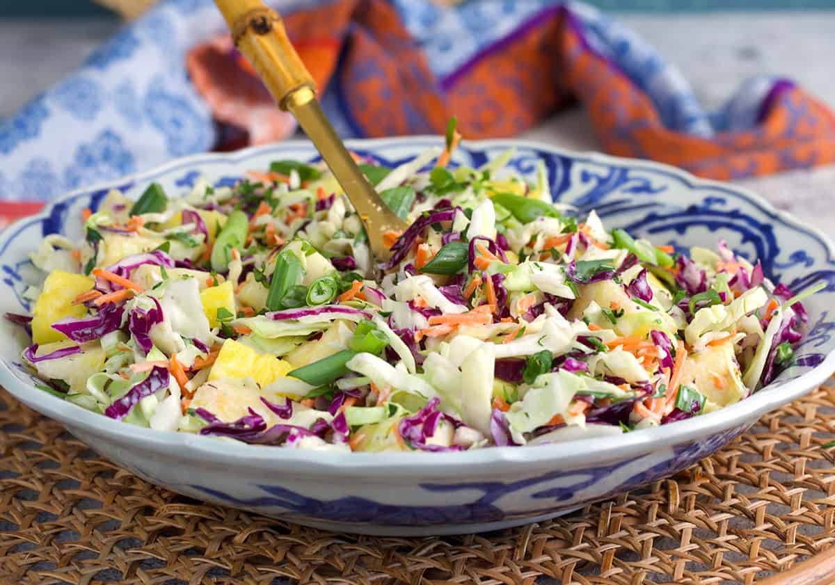 pineapple slaw in a serving bowl with a bamboo serving spoon