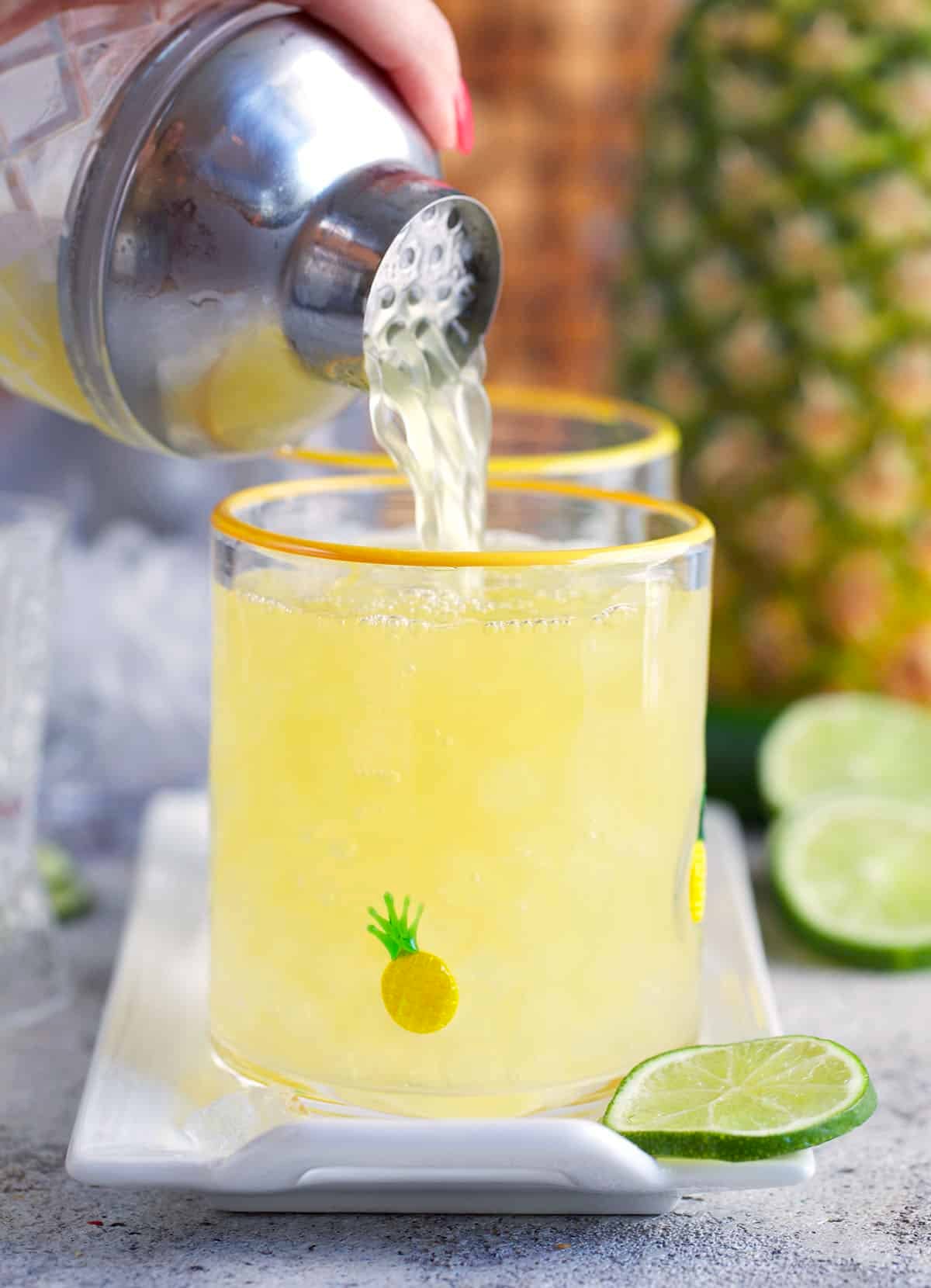 pineapple margarita being poured into a cocktail glass