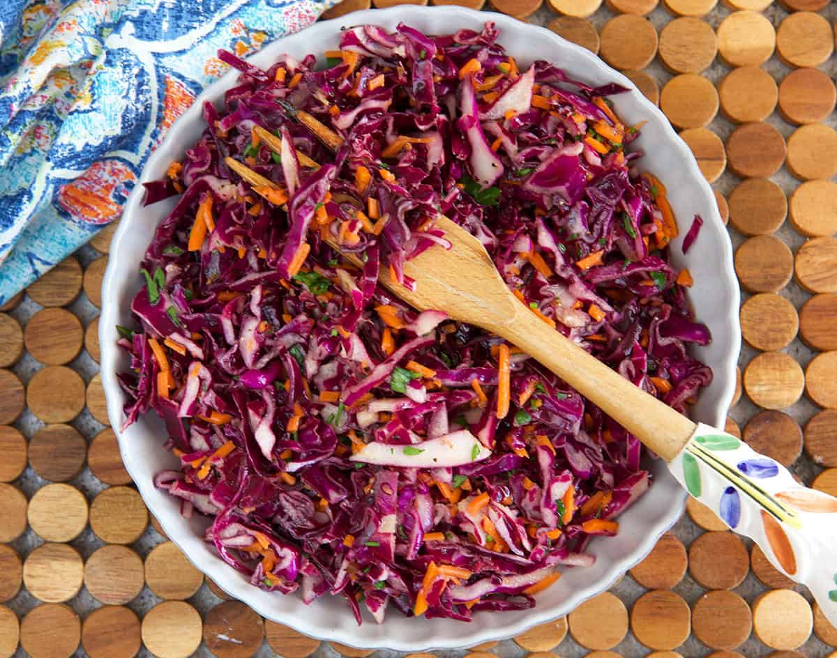 Red Cabbage Slaw in a white serving bowl with a serving fork.