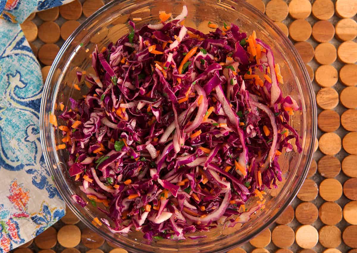 red cabbage slaw in a glass bowl mixed together.