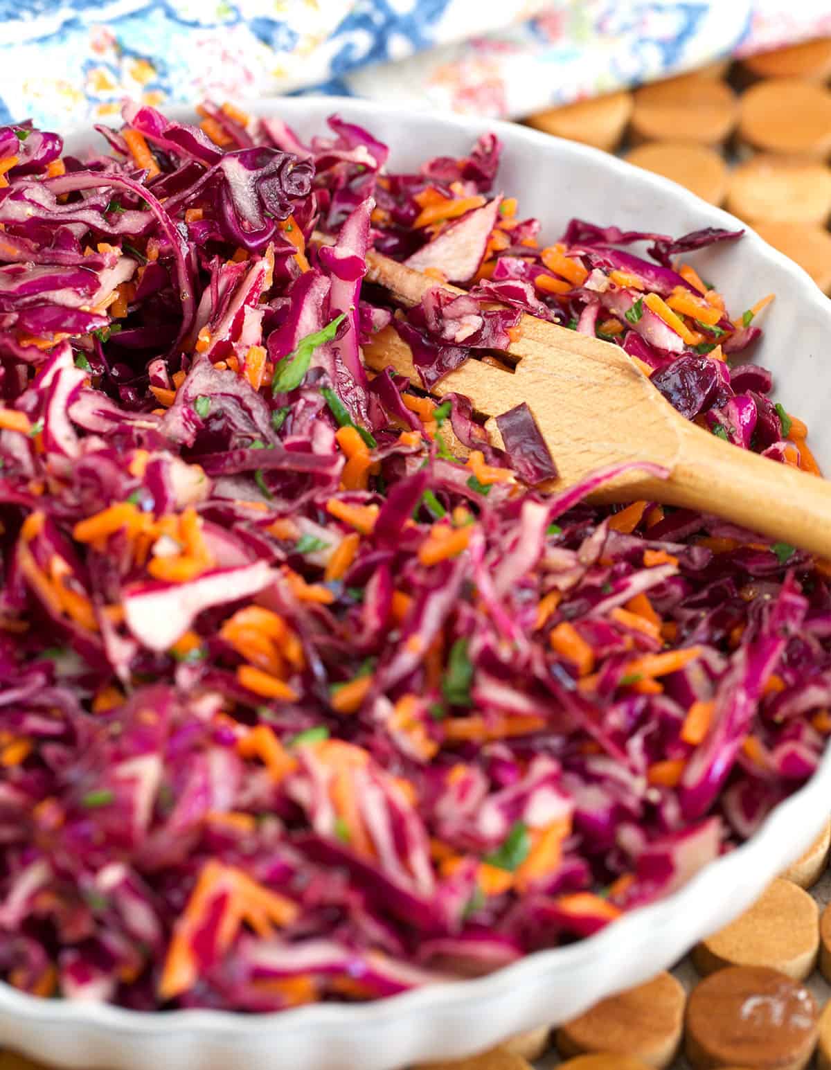 Red Cabbage Slaw served in a white bowl with a wooden serving fork.