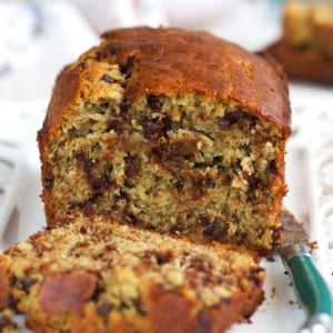 sourdough banana bread on a white platter, with a slice cut off.