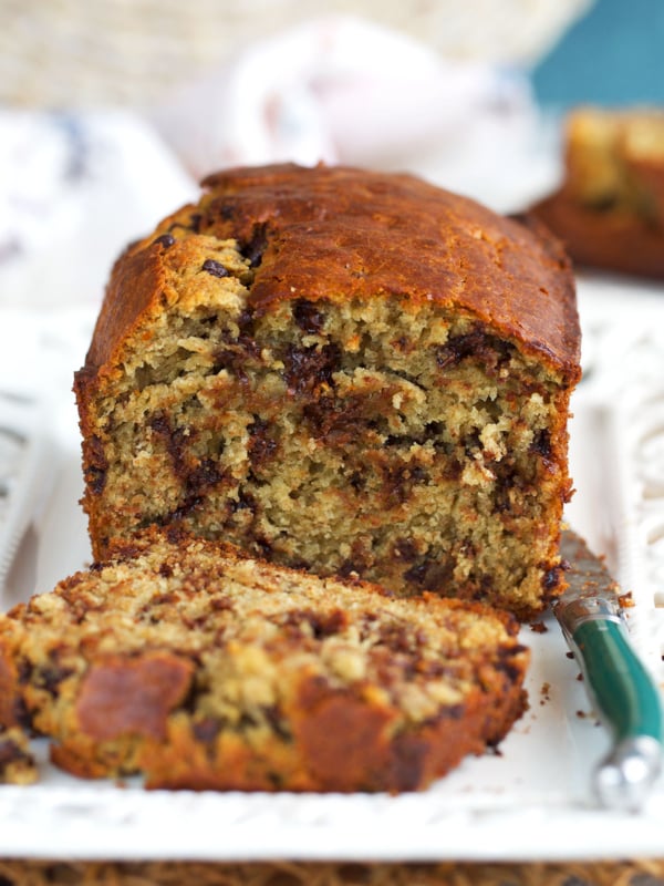 sourdough banana bread on a white platter, with a slice cut off.