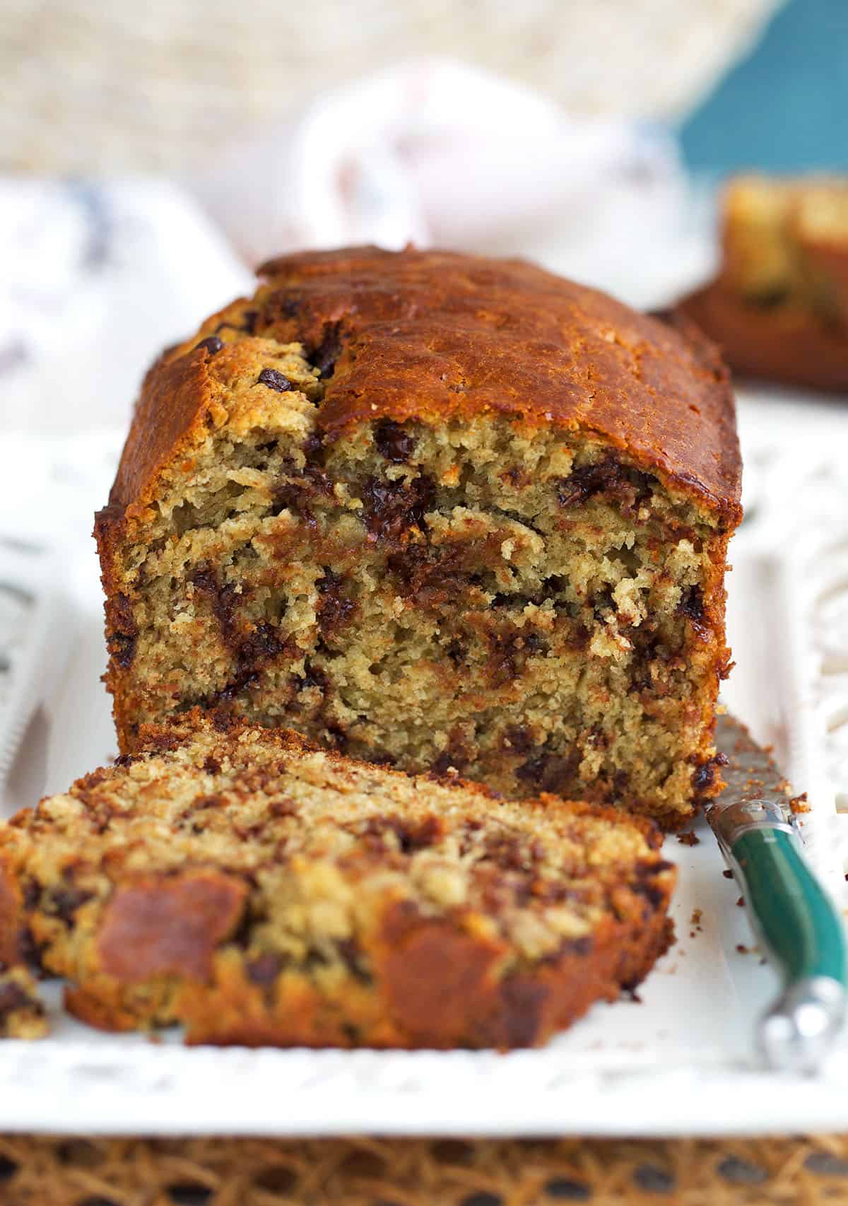 sourdough banana bread on a white platter, with a slice cut off.