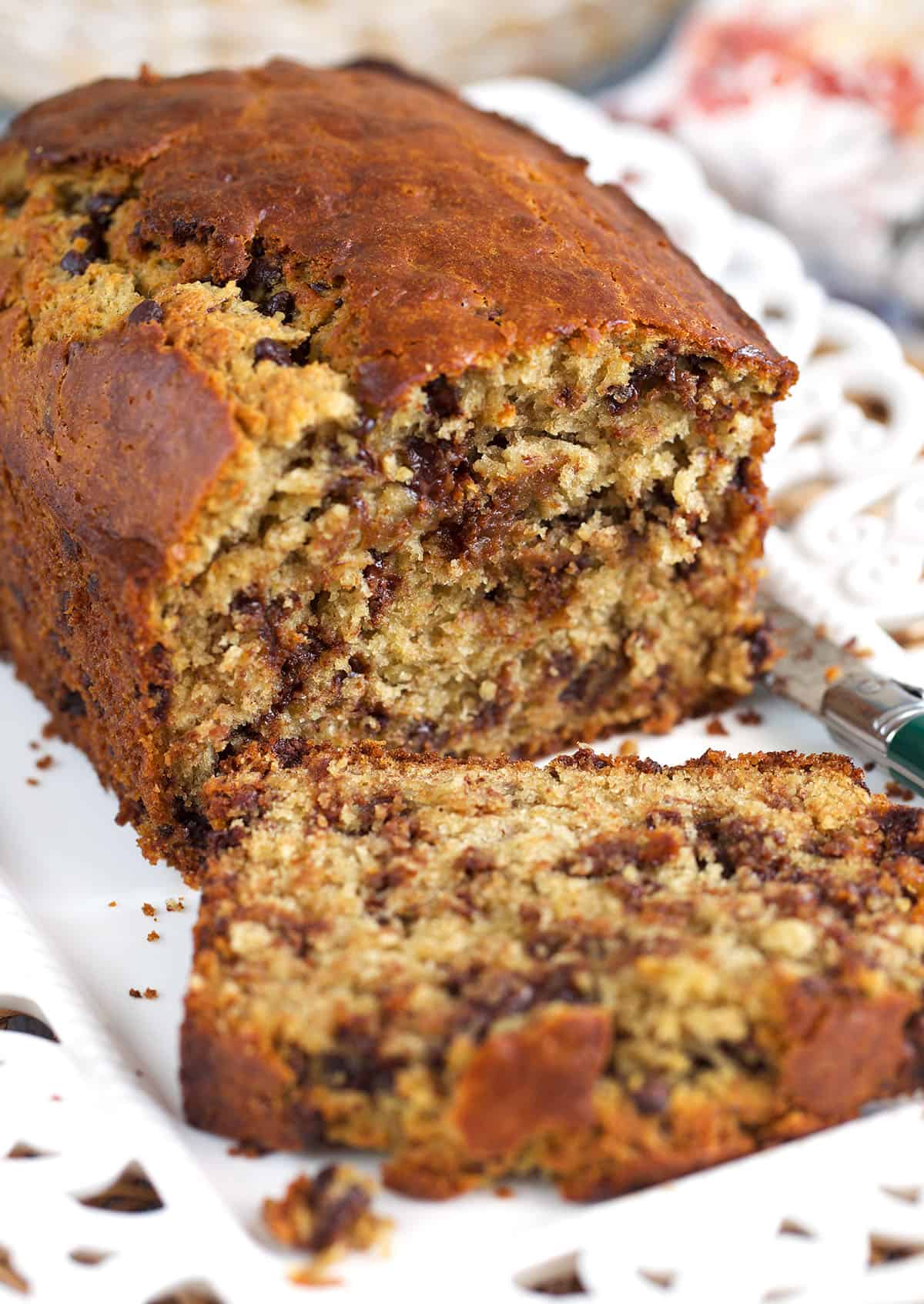 Sourdough banana bread with a slice cut off on a white platter.