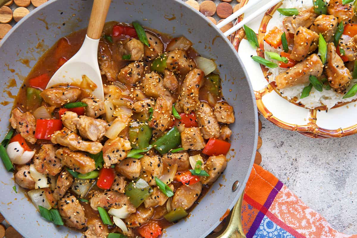 Sweet and sour pork in a nonstick stir fry pan and a plate with sweet and sour pork over rice.