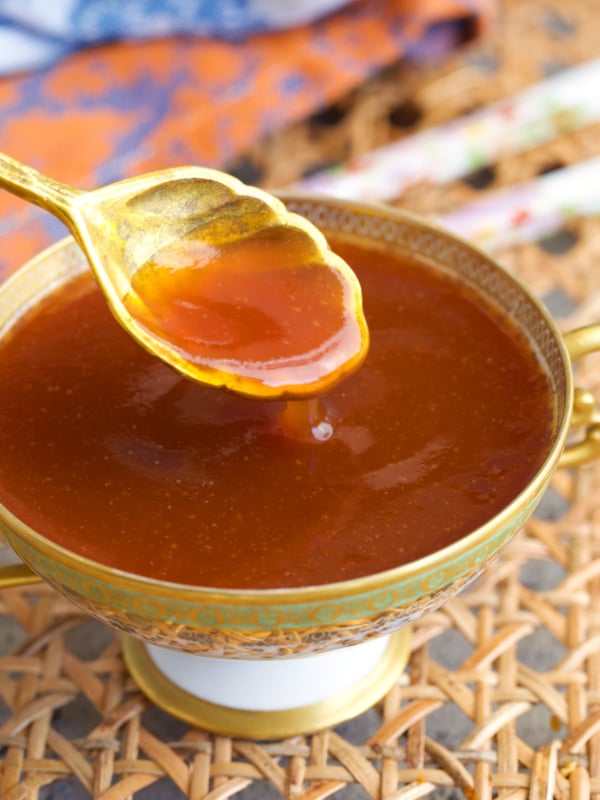 sweet and sour sauce in a compote dish with a gold spoon.