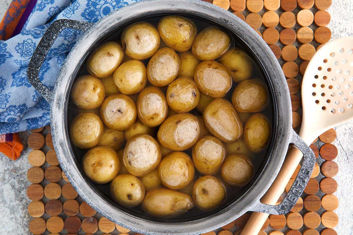baby new potatoes in a salty water bath in a black cast iron pot