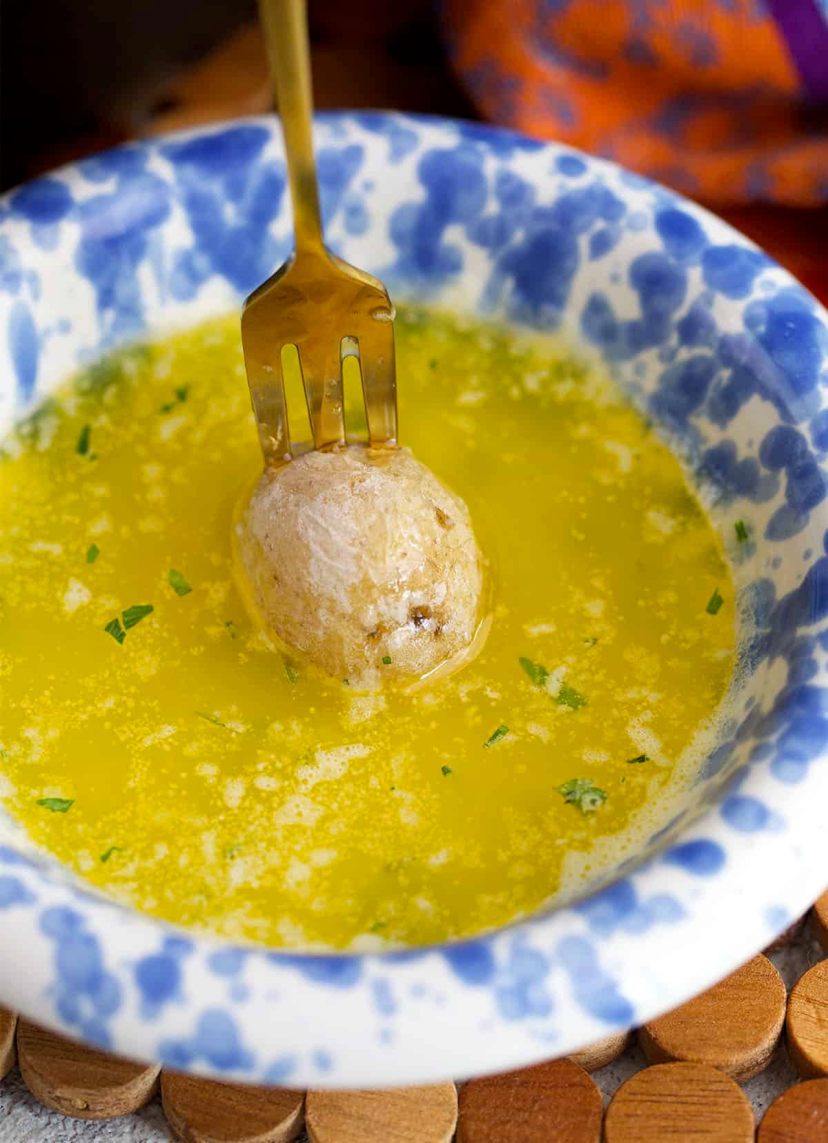 Salt potato on a gold fork being dunked into melted butter