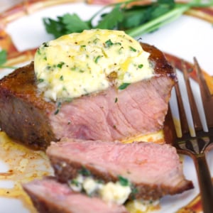 Air fryer sirloin steak topped with cowboy butter on a plate with a fork.