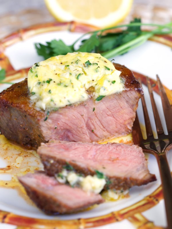 Air fryer sirloin steak topped with cowboy butter on a plate with a fork.