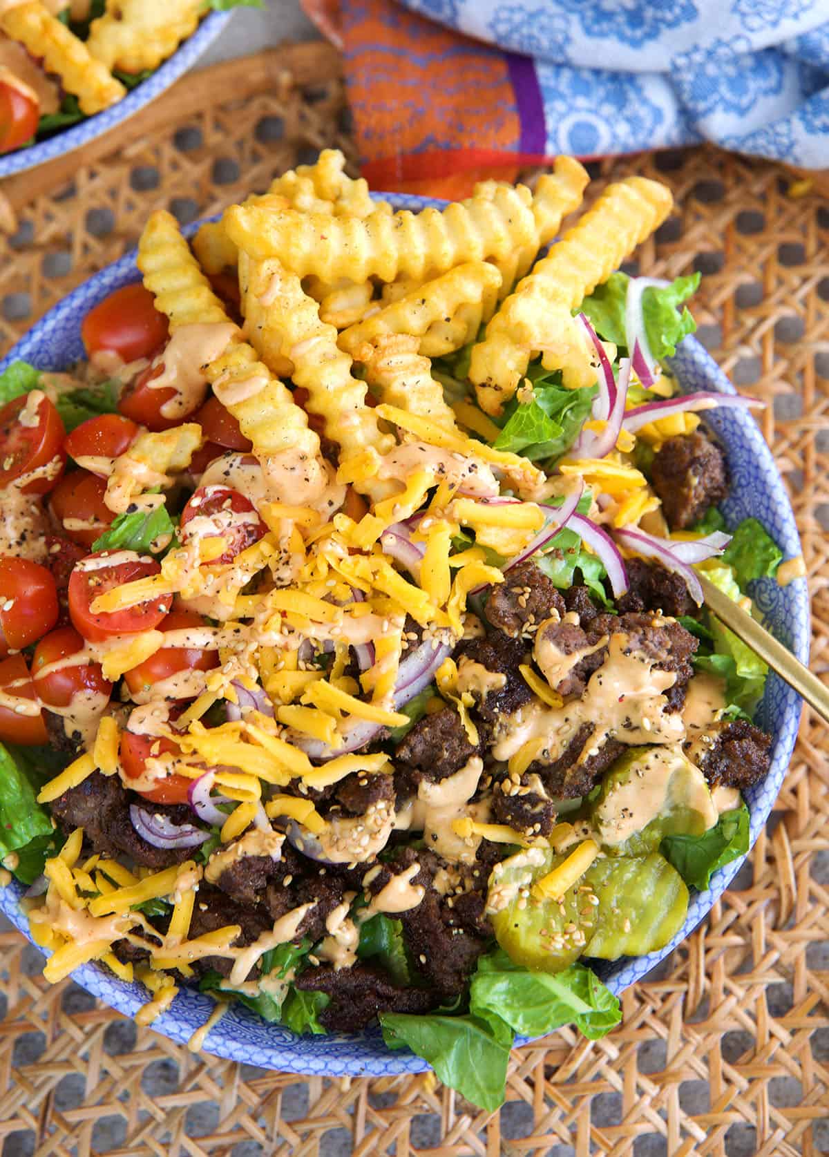 Burger Bowl on a placemat with French fries, pickles, lettuce and tomato