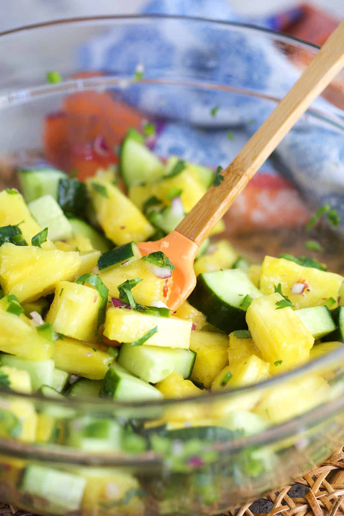 pineapple cucumber salad in a mixing bowl being tossed with a spatula