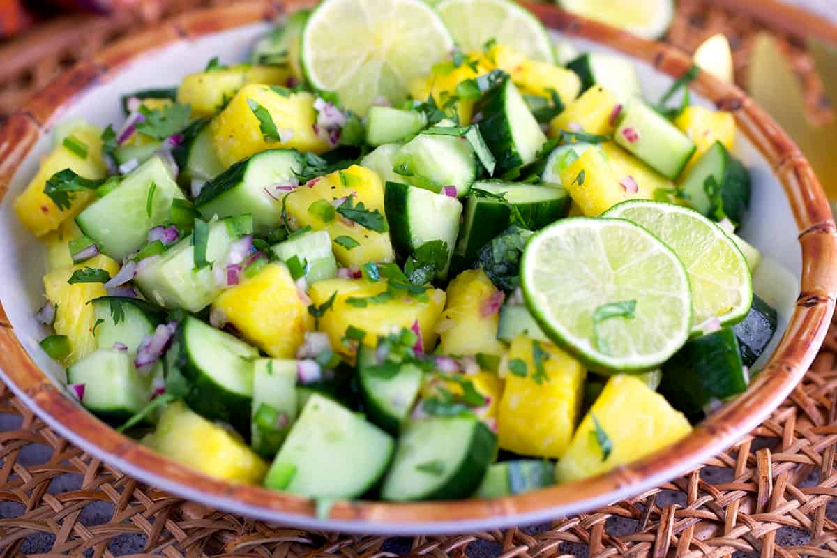 cucumber salad with pineapple in a large white serving bowl