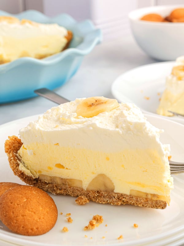 slice of banana cream pie on a plate with vanilla cookies.