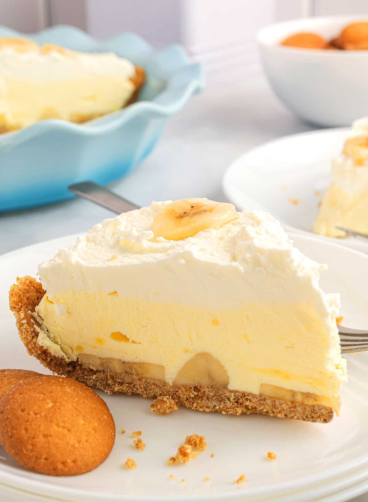 slice of banana cream pie on a plate with vanilla cookies.