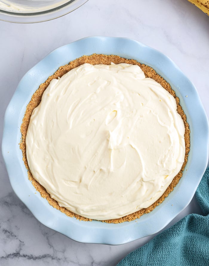 finished banana cream pie in a ceramic pie plate before being garnished.
