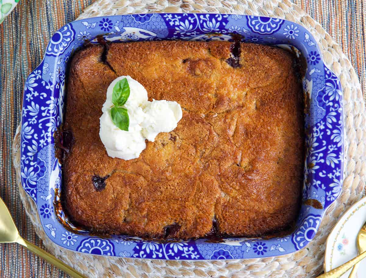 Cherry cobbler in a baking dish topped with three scoops of vanilla ice cream.