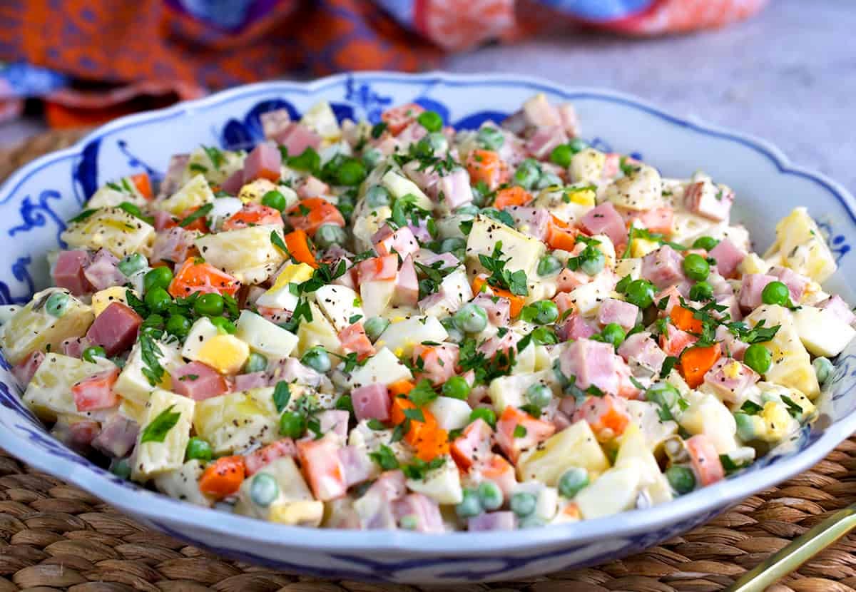 Russian salad in a serving bowl with a serving spoon