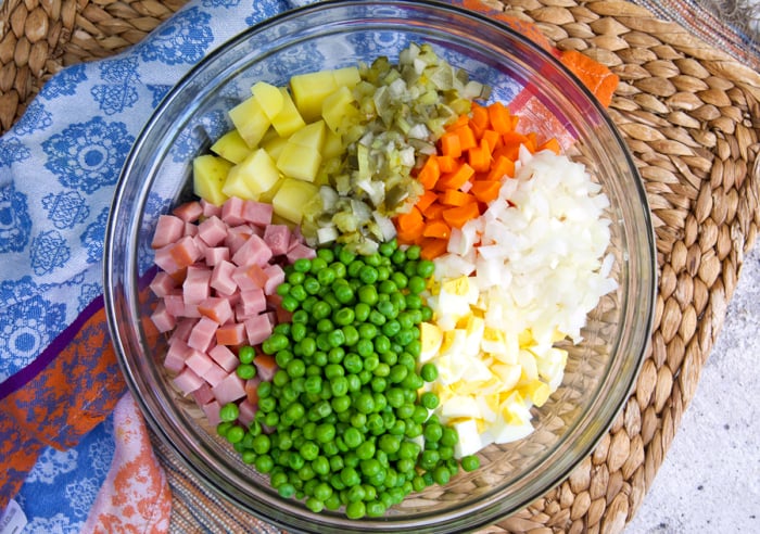 Ingredients for olivier salad in a glass mixing bowl