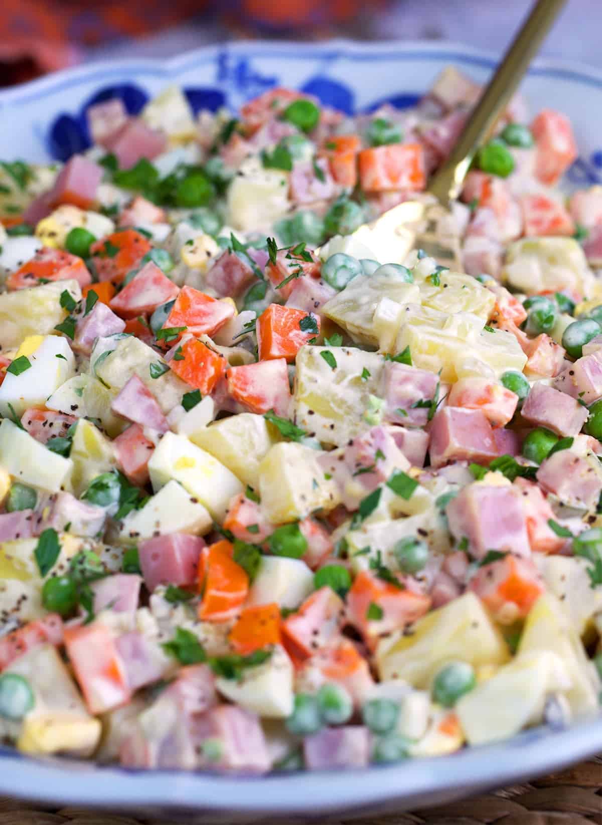russian salad in a bowl with a serving spoon