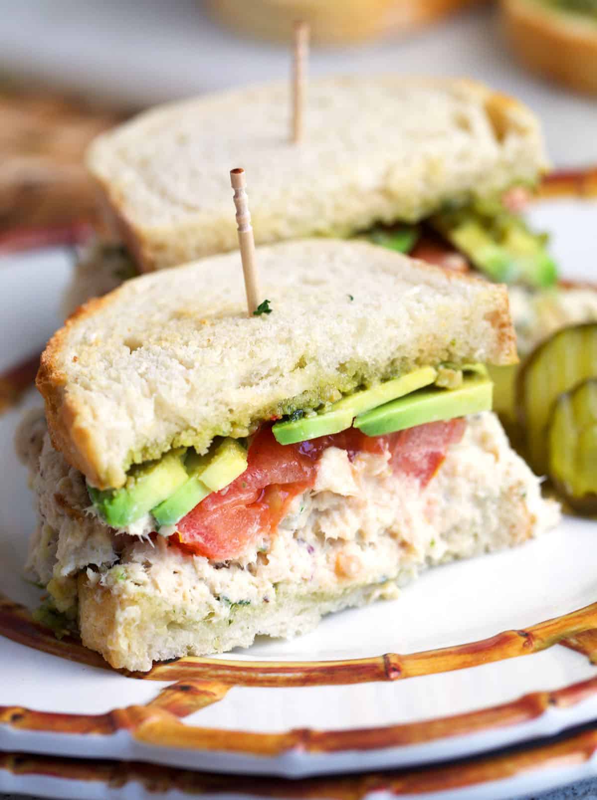 Tunacado sandwich cut in half on a plate.