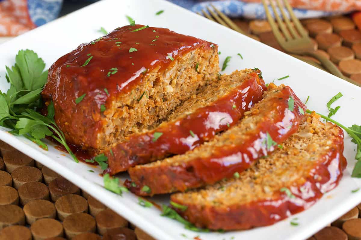 Turkey meatloaf with three slices on a white platter with parsley.