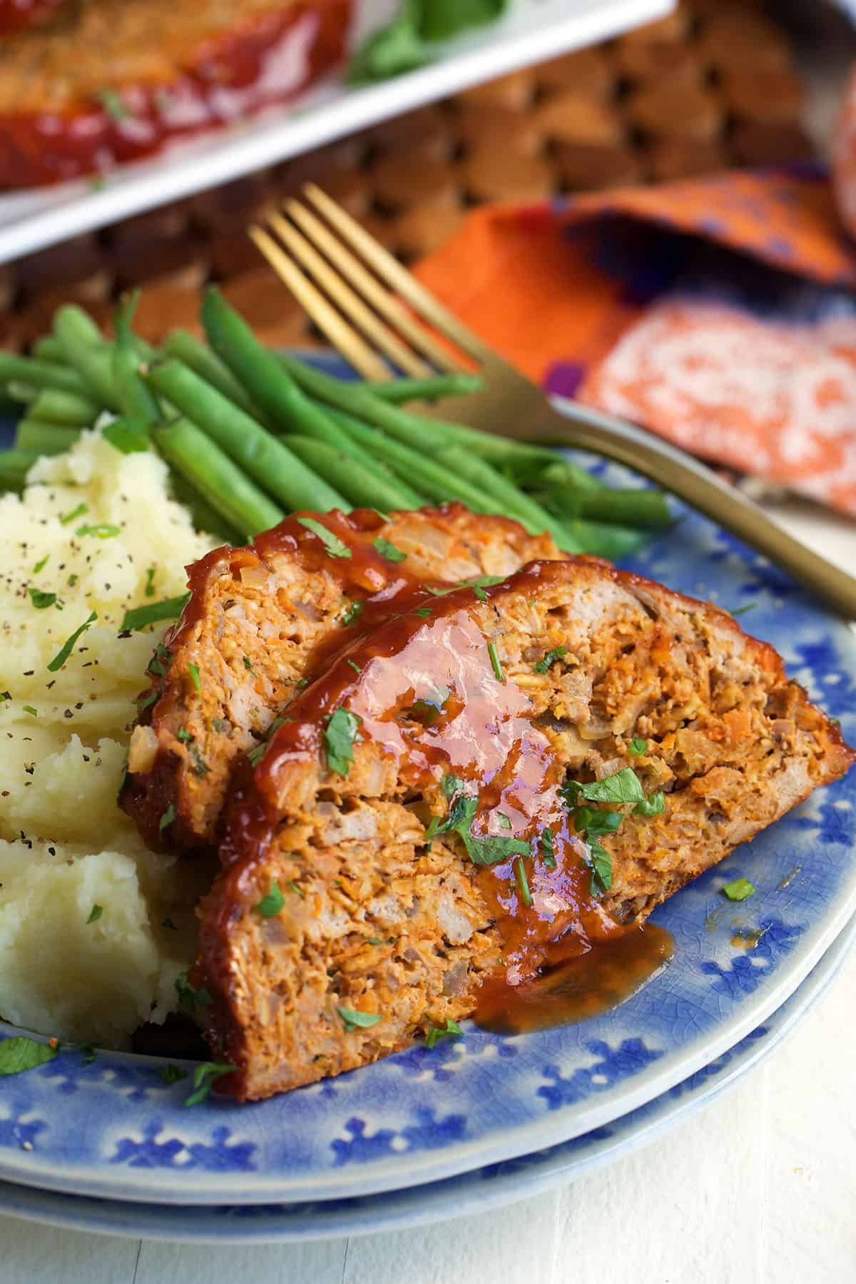 Turkey meatloaf slices on a plate with mashed potatoes and green beans