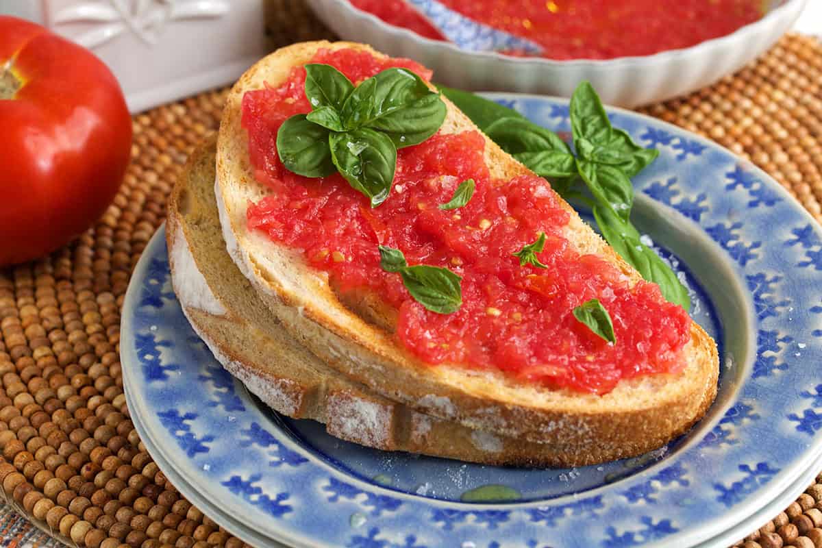 pan con tomato on a blue plate with a tomato in the background.