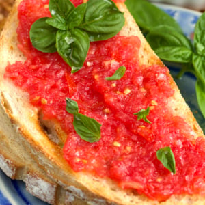 pan con tomate topped with fresh basil on a blue plate