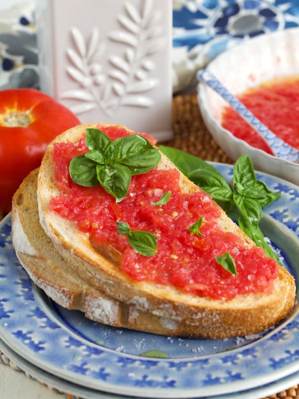 spanish tomato bread on a blue plate with a bottle of olive oil in the background