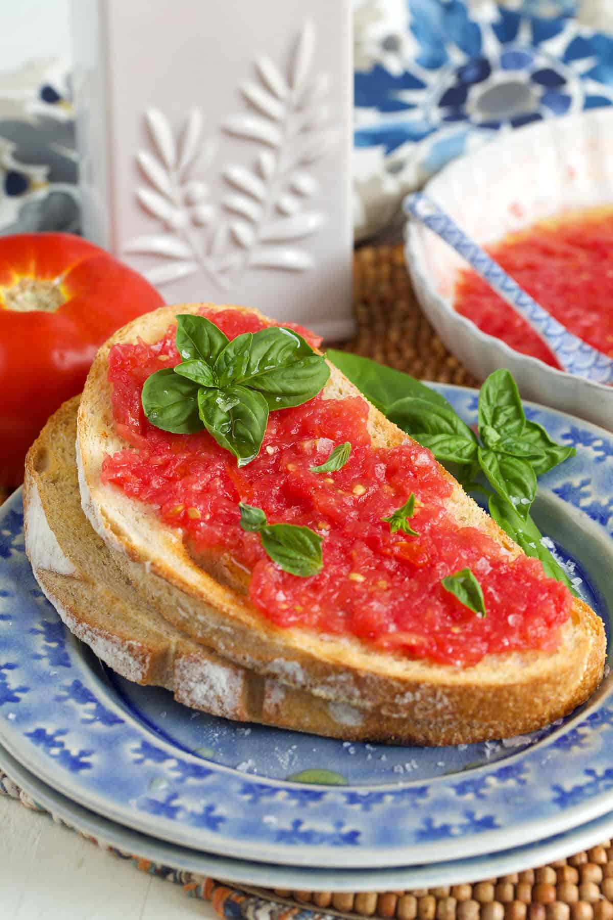 spanish tomato bread on a blue plate with a bottle of olive oil in the background