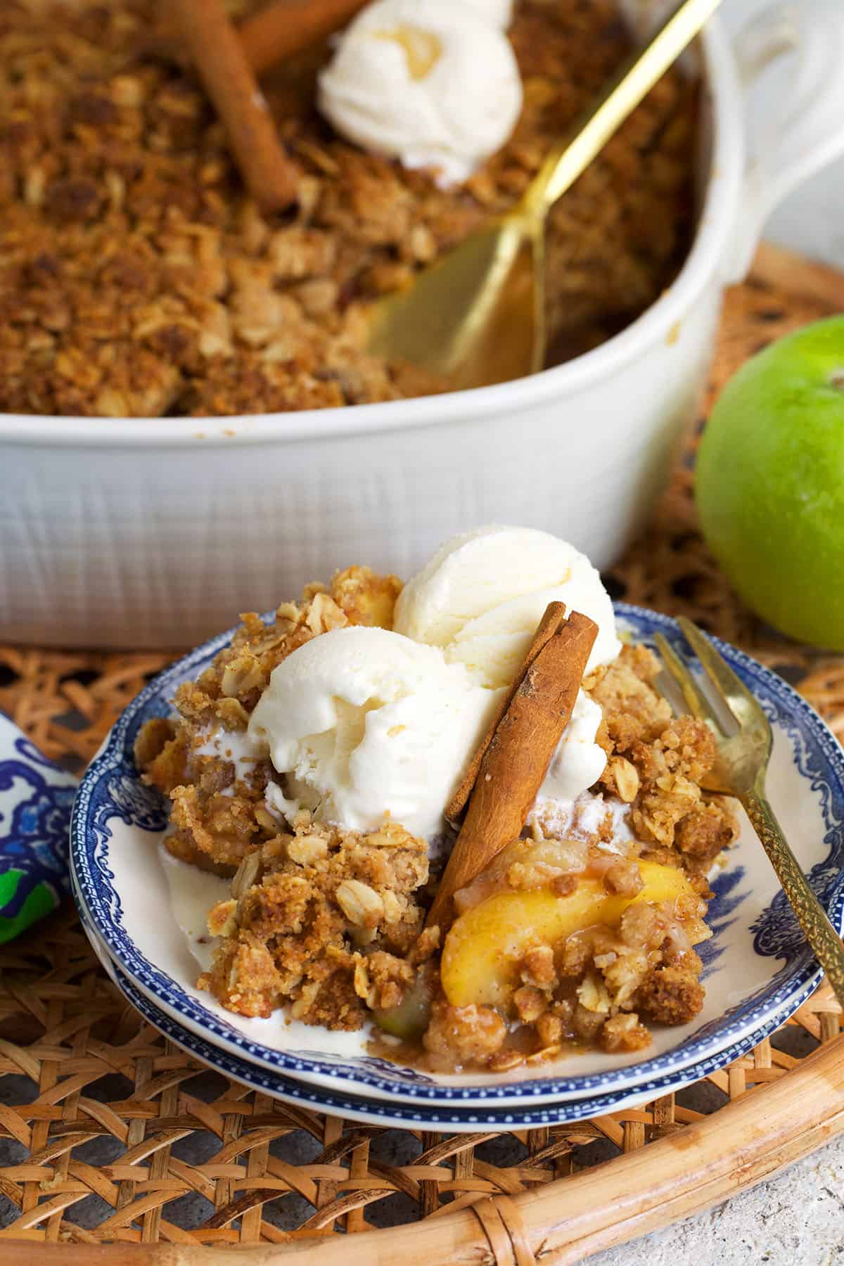 apple crumble on a blue and white plate with a casserole dish behind it.