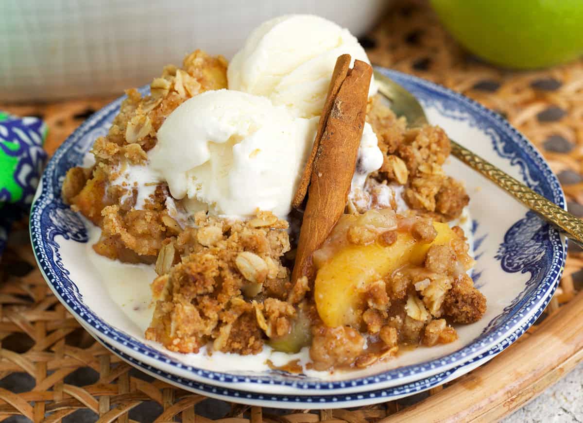 apple crumble recipe topped with two scoops of ice cream and a cinnamon stick