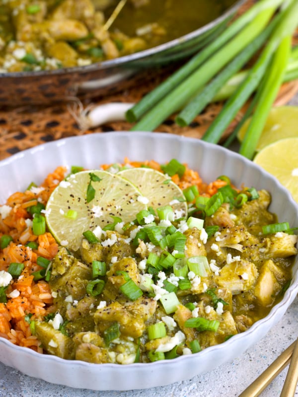Chicken Chile verde plated with rice and topped with cheese and cilantro.