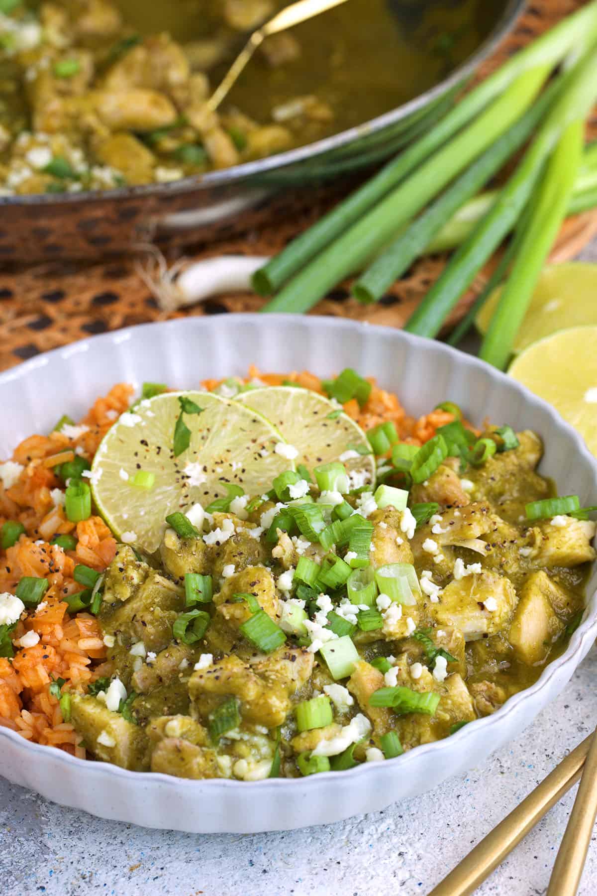 Chicken Chile verde plated with rice and topped with cheese and cilantro.