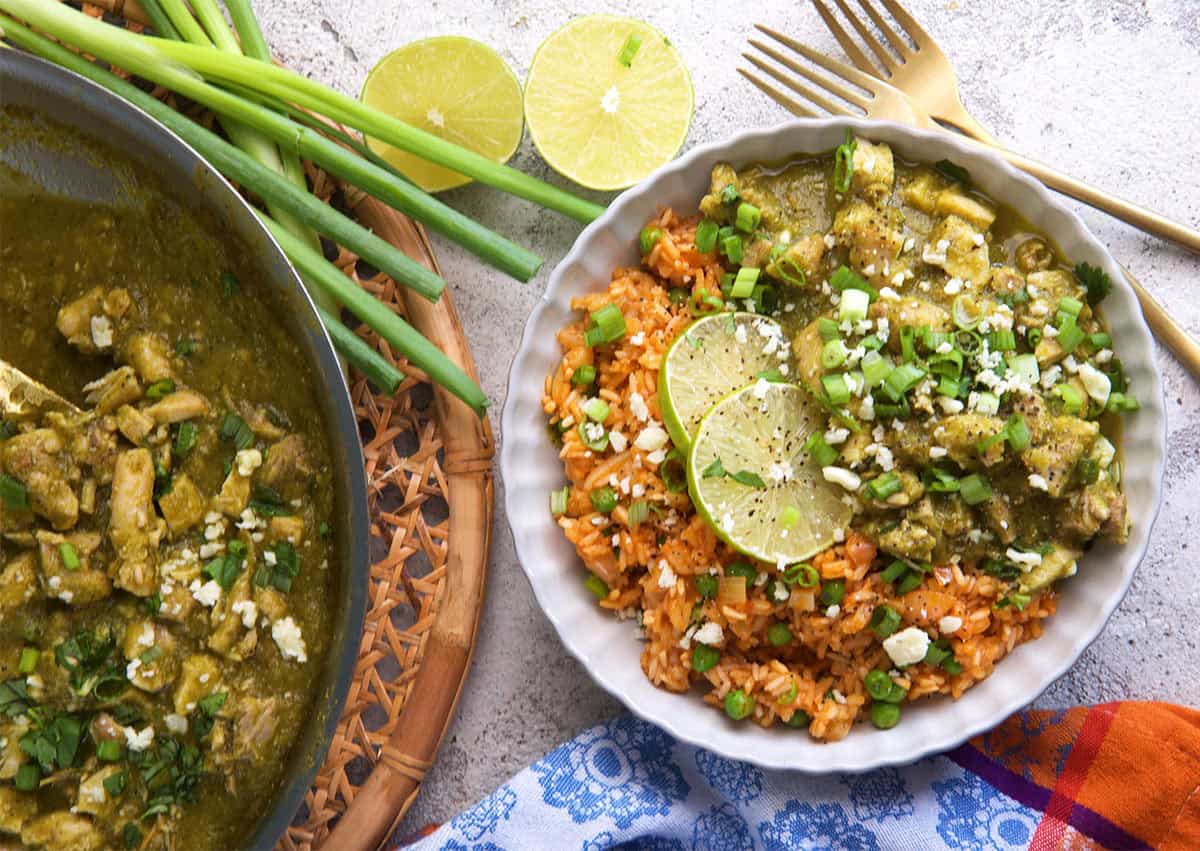 chicken Chile verde on rice with green onions and limes on the side.