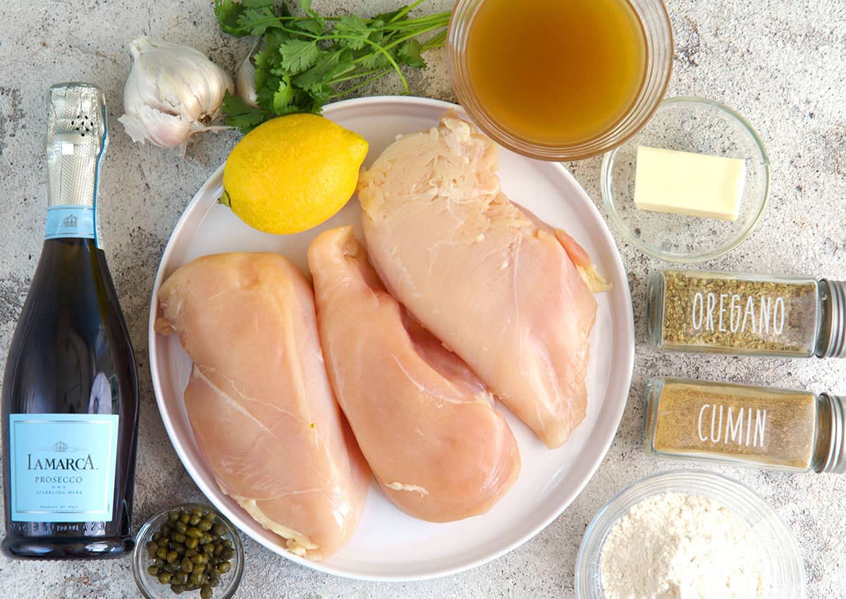 Ingredients for Chicken Piccata on a gray background.