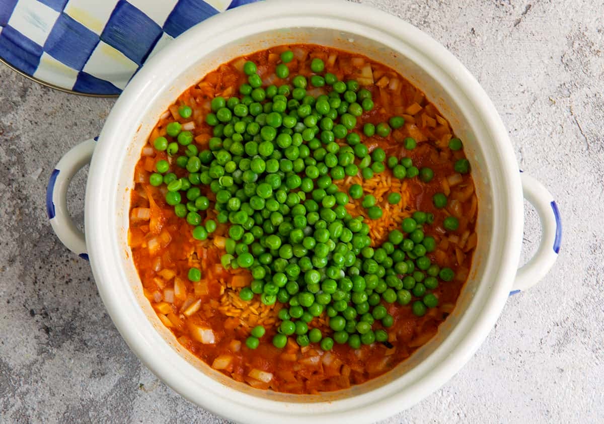 Mexican rice in a pot with peas on top to be stirred in.