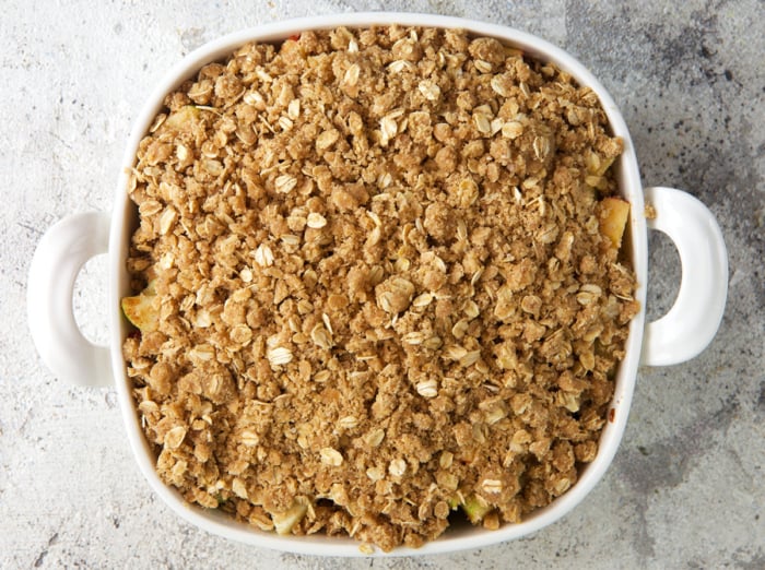 apple crumble on top of apples before baking