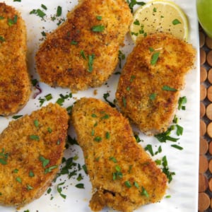 Breaded Pork Chops on a white platter with lemon slices
