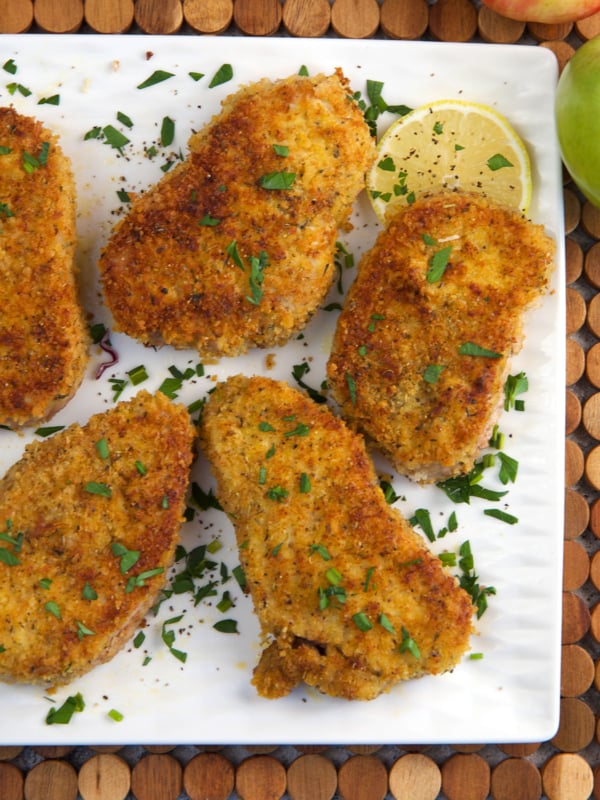 Breaded Pork Chops on a white platter with lemon slices