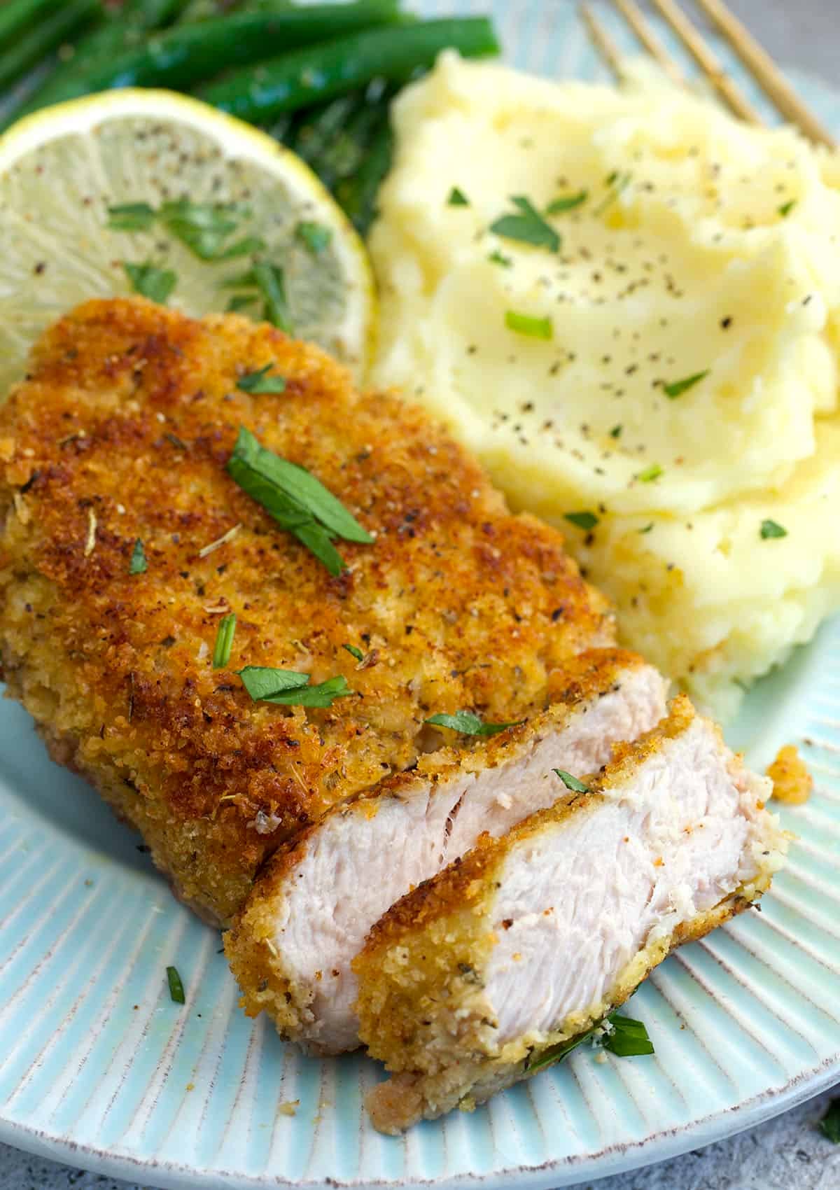 sliced breaded pork chop on a plate with mashed potatoes