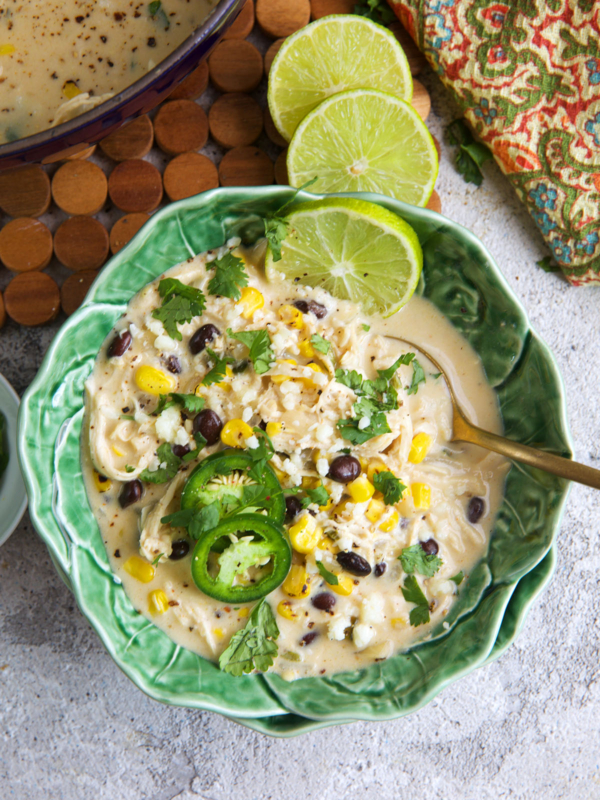 Chicken Poblano Soup in a cabbage ware bowl with limes on top.