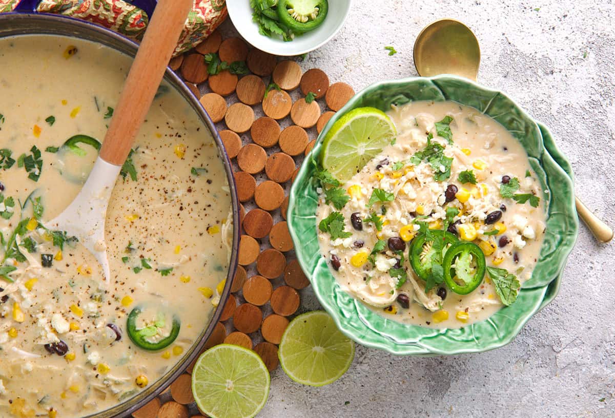 Chicken poblano soup in a bowl with a pot of soup to the left.